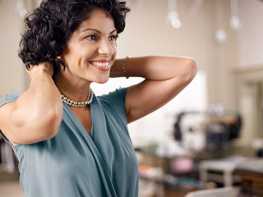 woman putting on pearl necklace